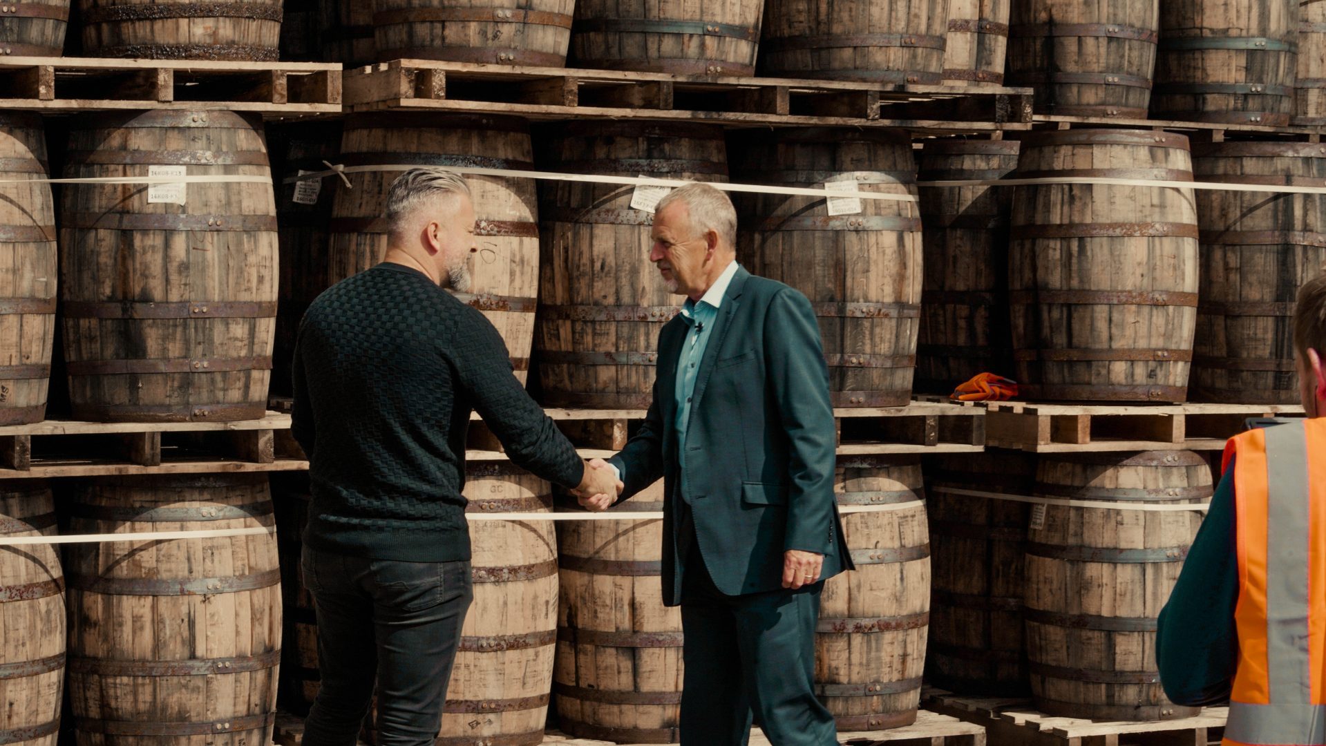 杰·布拉德利 (Jay Bradley) 和一位威士忌爱好者就威士忌酒桶投资交易握手