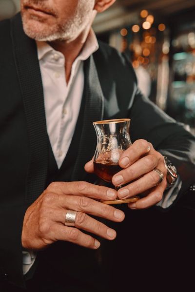 A person celebrating world whisky day with a glass of luxury scotch whisky