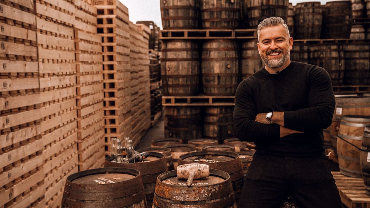 Jay bradley, whiskey connoisseur standing in front of casks of whiskey